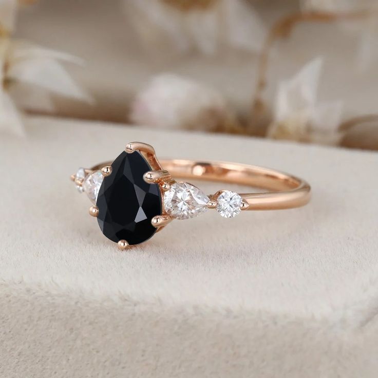 a black and white diamond ring sitting on top of a cushioned surface with flowers in the background