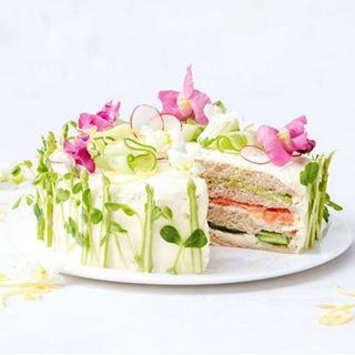 a white plate topped with a cut in half cake covered in cucumber and radishes