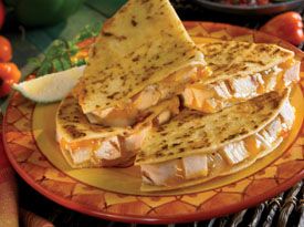 a plate topped with quesadillas on top of a table next to bowls of vegetables