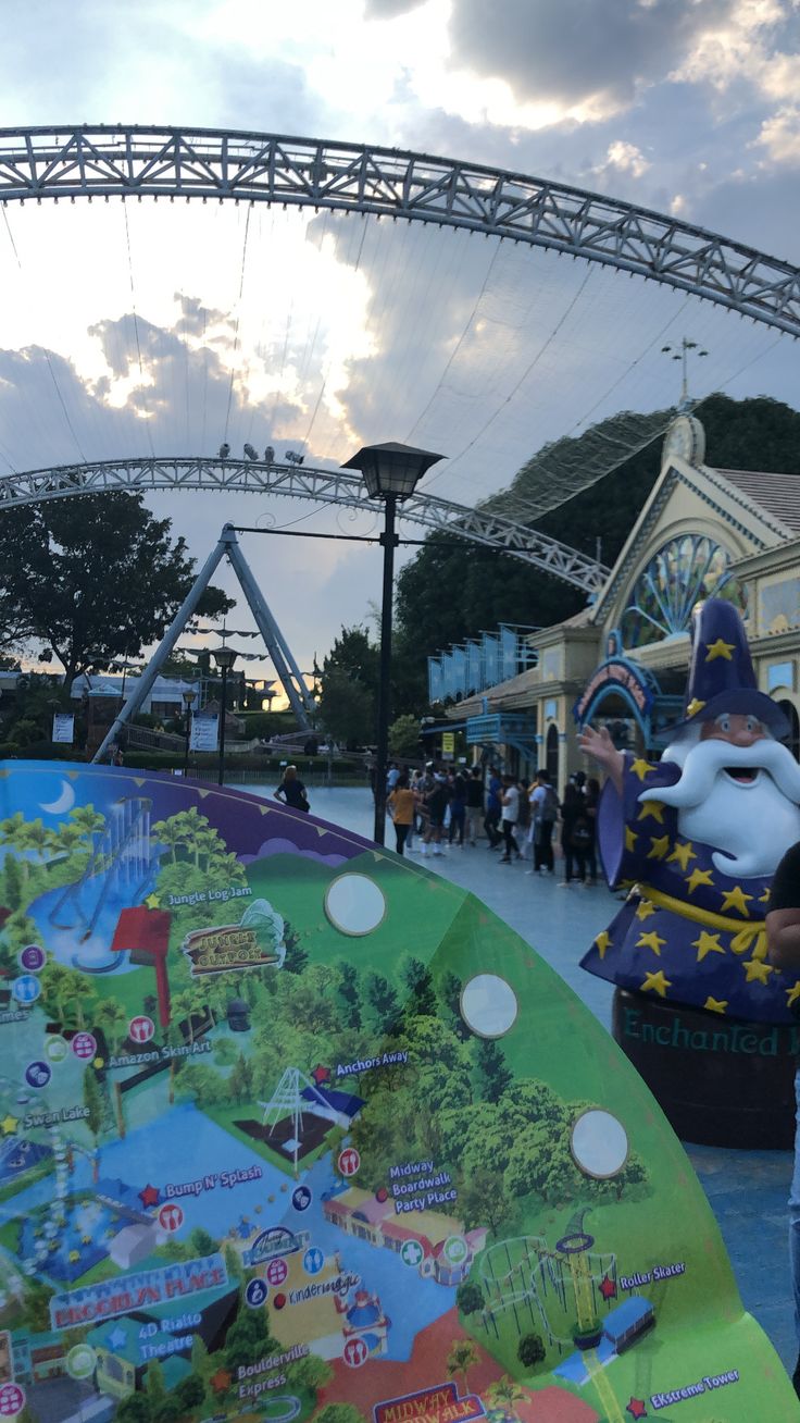 an amusement park with people standing around and looking at the map