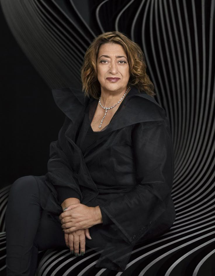 a woman sitting on top of a black chair next to a white and black wall