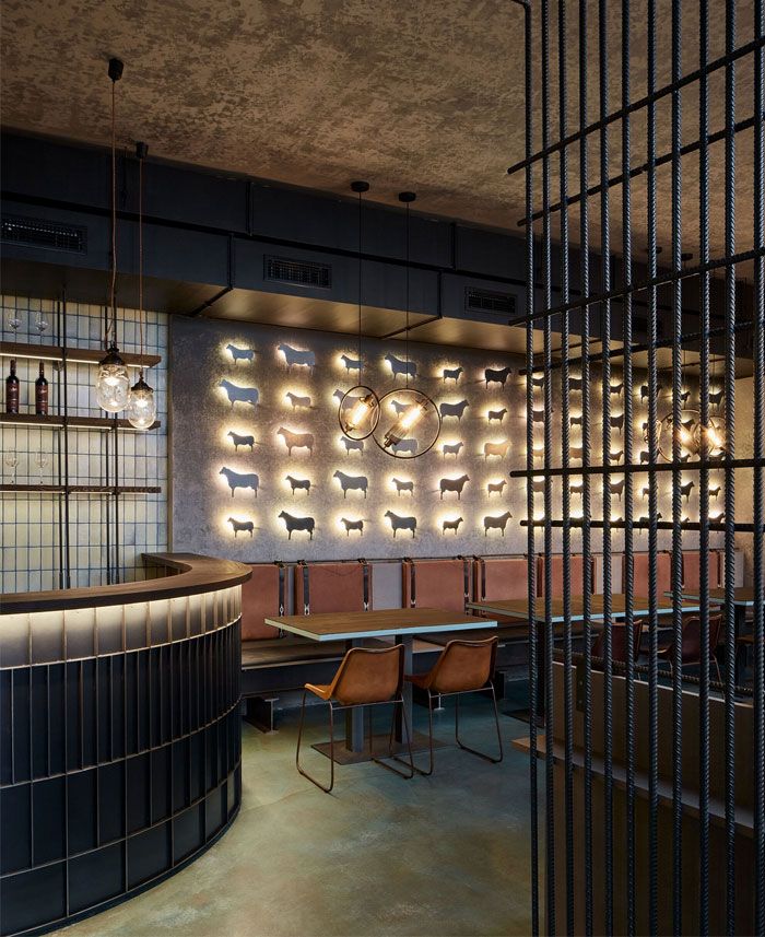 an empty restaurant with tables and chairs in front of a circular light fixture on the wall