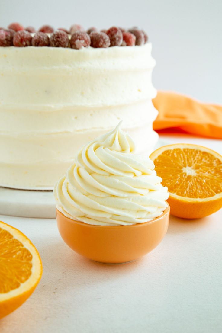 there is a cake with white frosting and orange slices around it