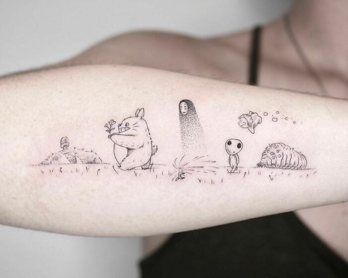 a person with a tattoo on their arm that has an image of cartoon characters in the background