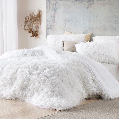 a bed with white fluffy blankets and pillows