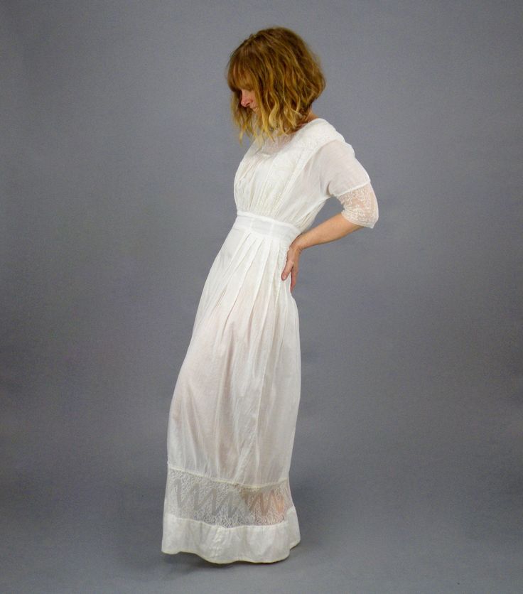 "Antique Edwardian white cotton lace lingerie dress. Styled with a square cut cotton neckline with short vertical pin tucks featuring a dainty floral net lace center inset along with lace shoulder bands extending to the waistline. Gathered center bust, 1/2 length lace trimmed dolman sleeves, wide banded nipped waistline and flowing floor length skirt with flattering vertical tuck seams and horizontal lace inset near hem. The dress closes up the back with hook and eyes. Label: None Content: Semi- Elegant Empire Waist Prairie Dress For Daywear, Elegant Prairie Dress With Empire Waist For Daywear, Fitted Cotton Dress With Delicate Lace, Cotton Delicate Lace Dress For Daywear, Elegant Lace Prairie Dress For Daywear, Daywear Lace Dress, Feminine Victorian Dress With Lace Trim For Daywear, Fitted Feminine Victorian Dress For Daywear, Feminine Fitted Victorian Dress For Daywear