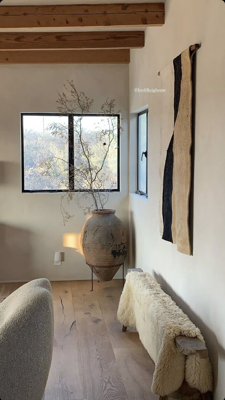 a large vase sitting on top of a wooden floor in a living room next to a window