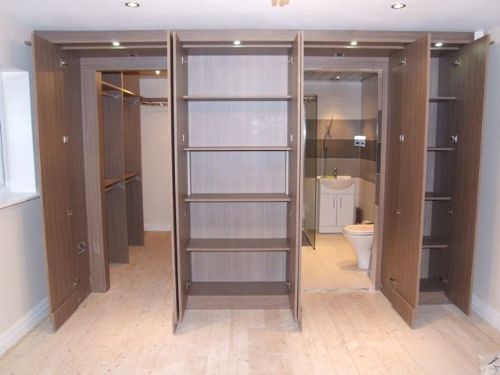 an empty walk in closet next to a toilet and cabinets with lights on the ceiling