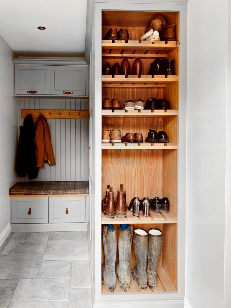 the inside of a walk in closet with boots and coats on shelves next to each other