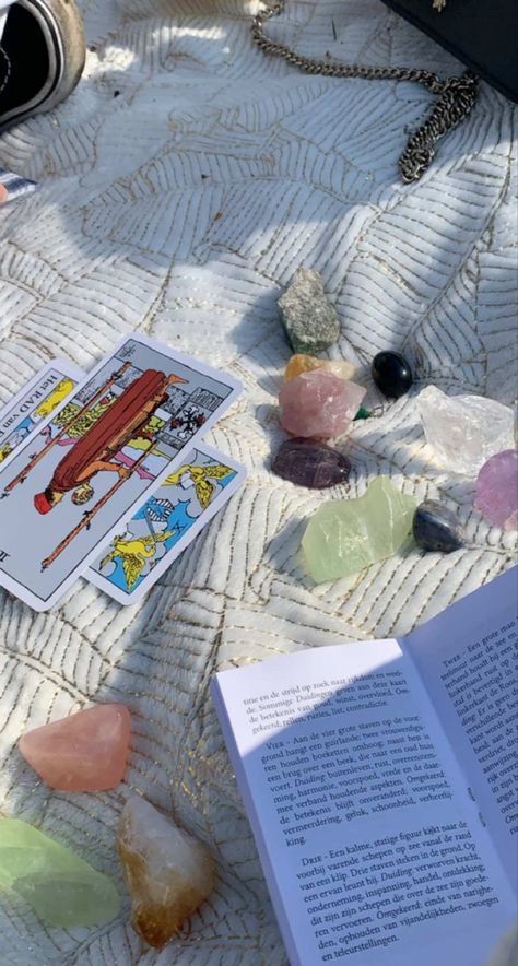 an open book sitting on top of a white blanket next to rocks and other items