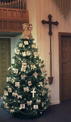 a decorated christmas tree in front of a church with pictures on it and a crucifix