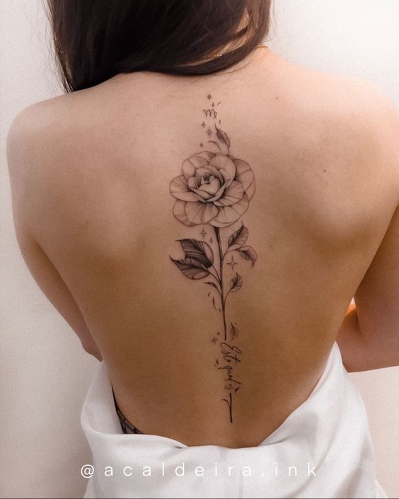 the back of a woman's neck with a rose tattoo on it and writing in cursive font