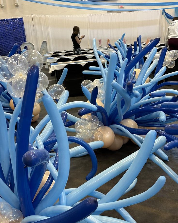 blue and white balloons in the shape of trees are on display at an art show