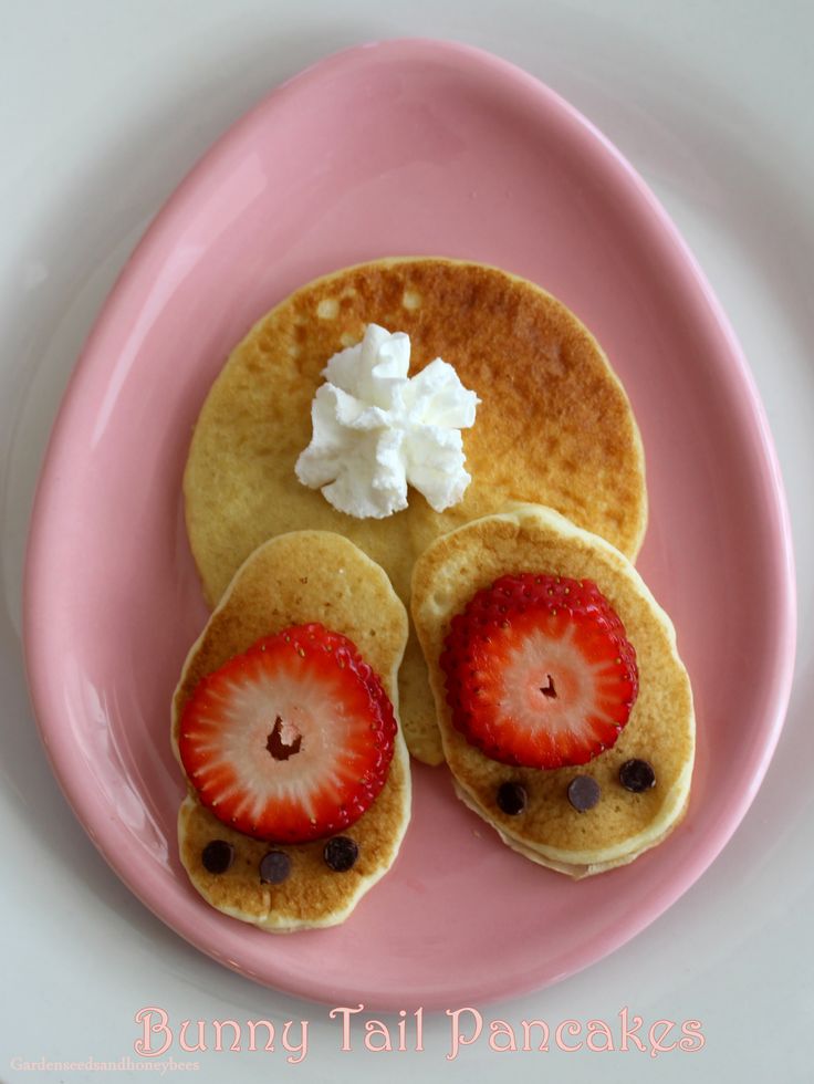 pancakes with strawberries and whipped cream are on a pink plate