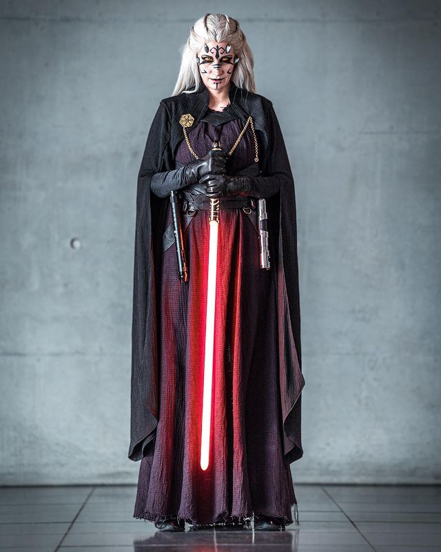 a woman dressed as darth vader standing in front of a wall