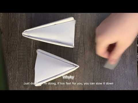 two white paper cones sitting on top of a wooden table next to a person's hand