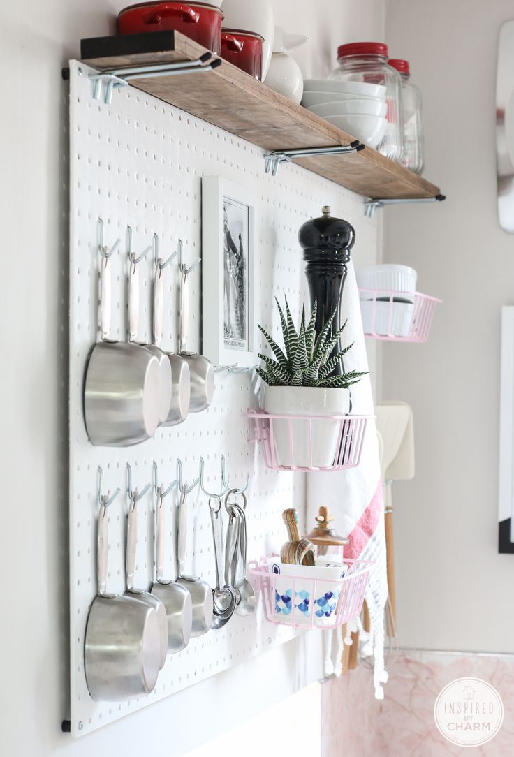 a kitchen wall with pots and pans hanging on it's sides, along with utensils