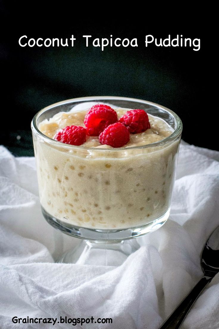 a glass bowl filled with pudding and raspberries on top of a white cloth