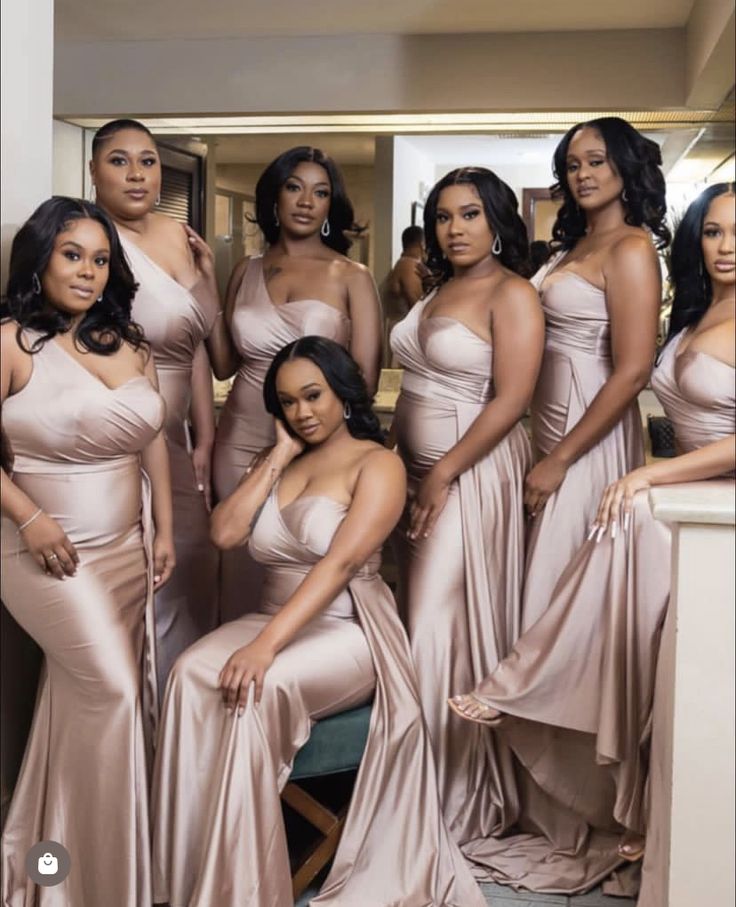 a group of women standing next to each other in long gowns and posing for the camera