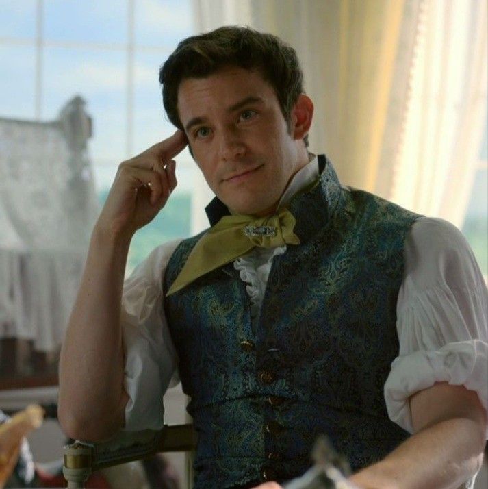 a man wearing a vest and bow tie sitting in a chair with his hand on his head