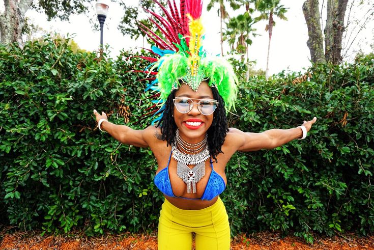 a woman in yellow pants and a colorful headdress is posing for the camera