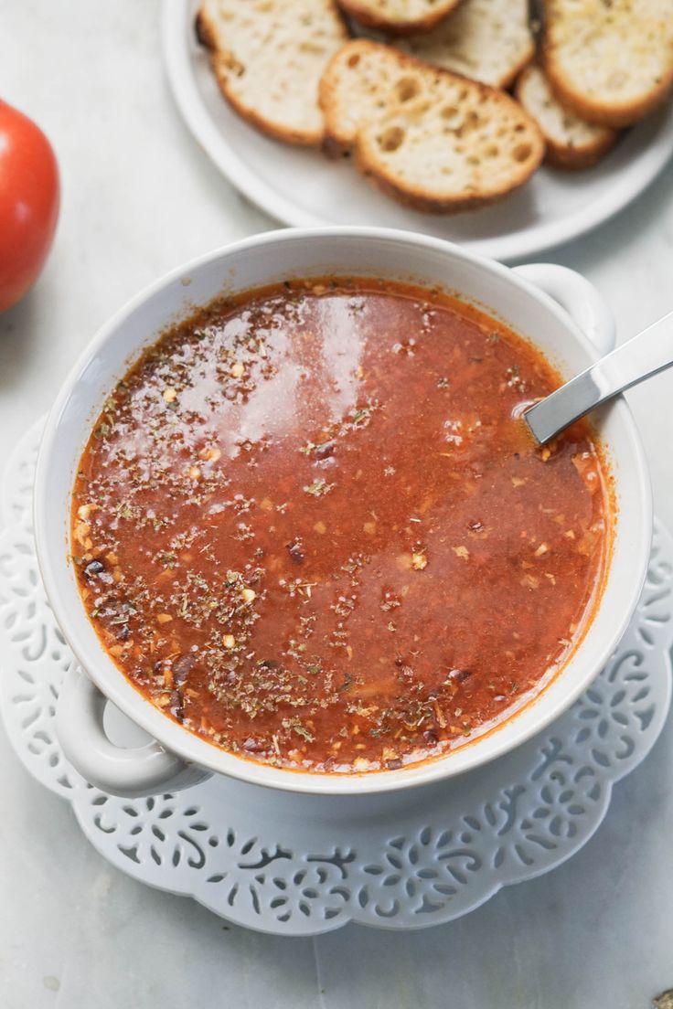 a bowl of tomato soup with bread on the side