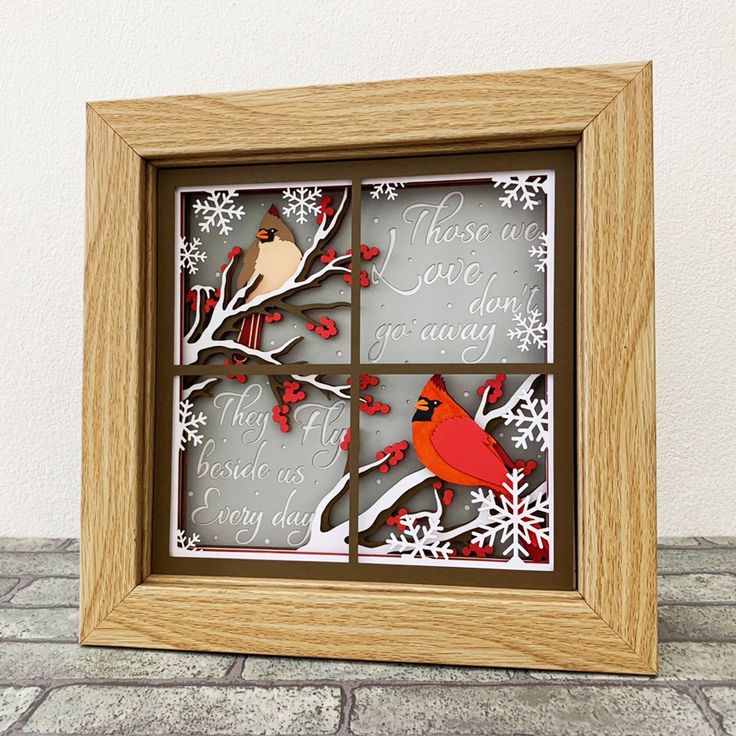 a wooden frame with cut out birds and snowflakes on the window sill