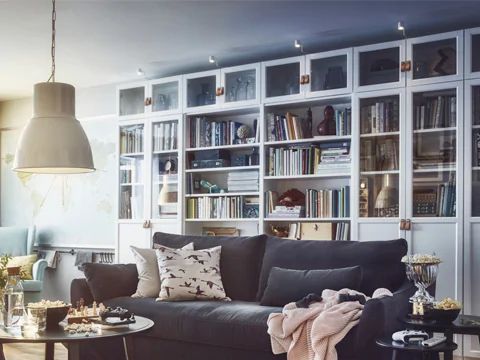 a living room filled with furniture and bookshelves next to a window covered in curtains