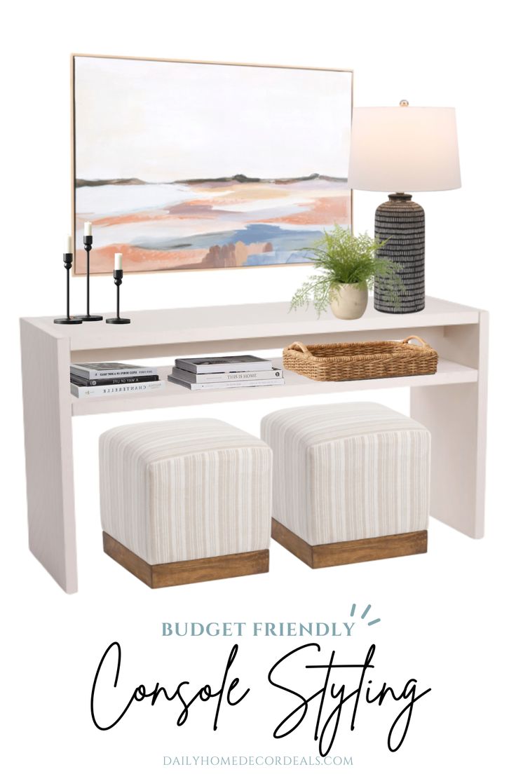 Affordable decor ideas for styling an open console table. Includes white wood console table with 2 square cube ottomans with beige and white striped pattern underneath. On the shelf is a woven wicker tray basket. On top of the console table is a black table lamp with a faux plant and 3 black metal candlesticks. Last, a budget-friendly framed watercolor artwork. The art is large oversized but very inexpensive featuring an abstract landscape of the seaside with blues, blushes, and gray tones. Console With Stools Underneath, Console Table With Cubes Underneath, Entry Table With Seating Under, Guest Bedroom Console Table, Console Table With 2 Stools, Console With Seating Underneath, Console With Ottoman, Ottoman Under Entry Table, Console Table With Stools Underneath