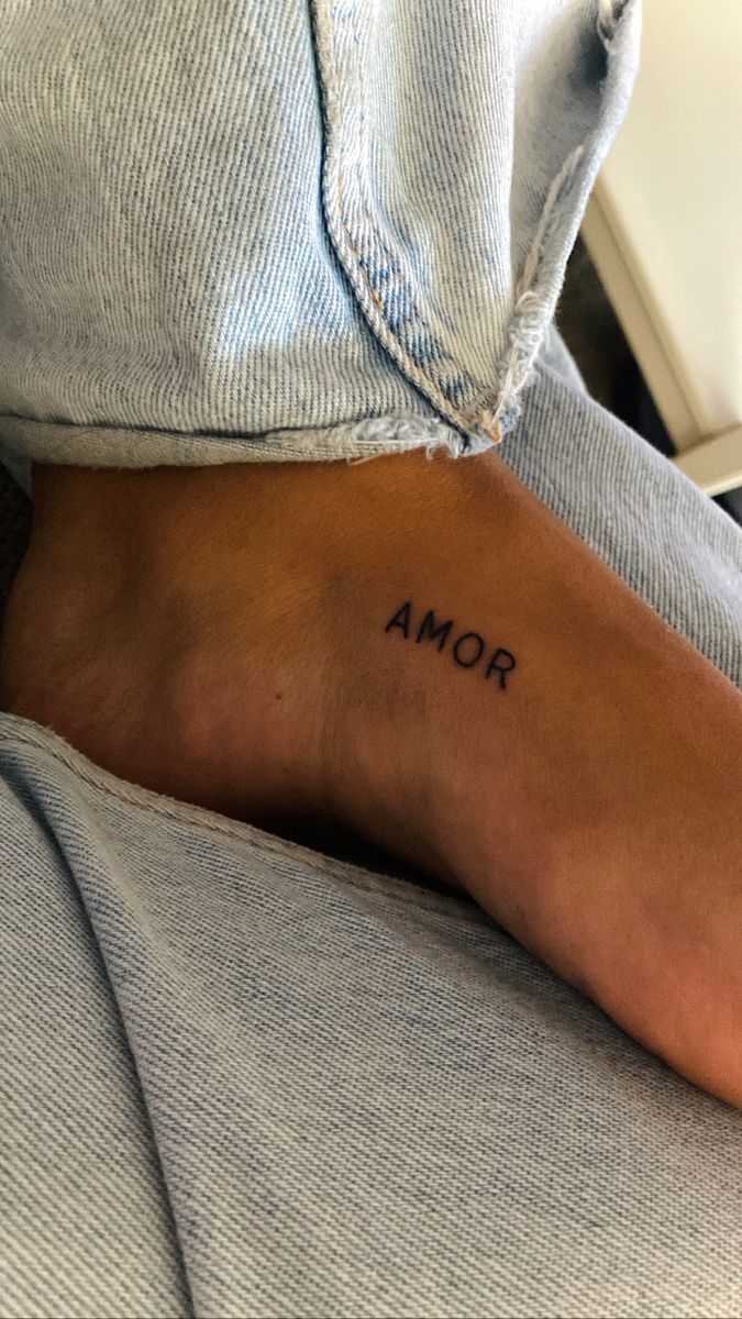 a person with a small tattoo on their left foot and the word roma written in black ink