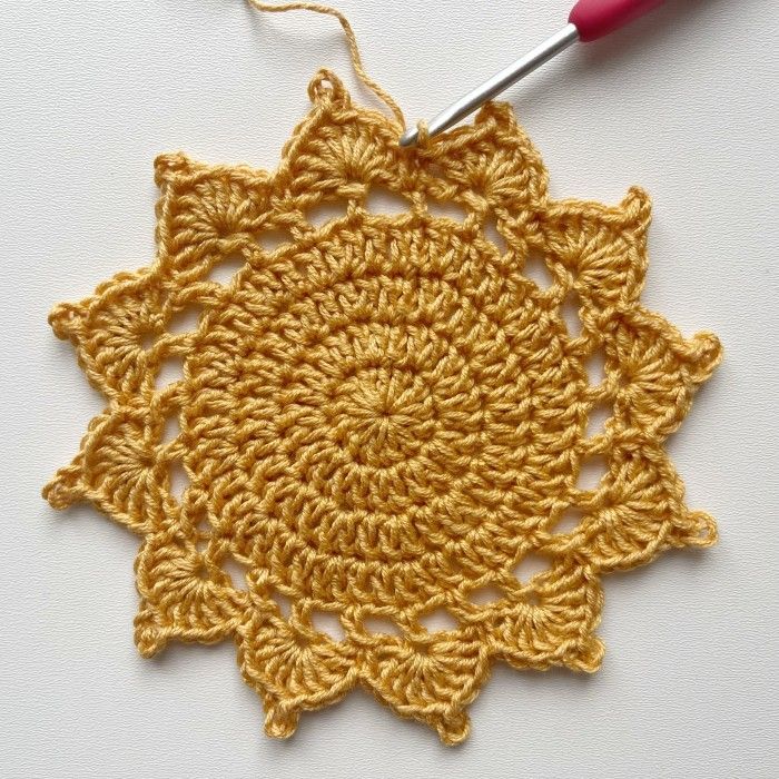 a crocheted doily with a red hook