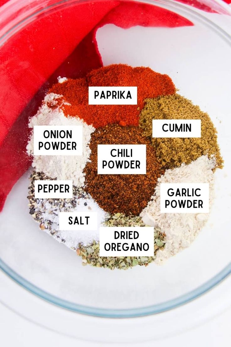 spices in a glass bowl labeled with the ingredients to make homemade chili seasoning recipe