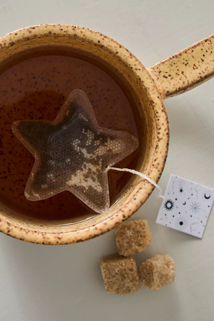 a star shaped tea in a mug next to some sugar cubes