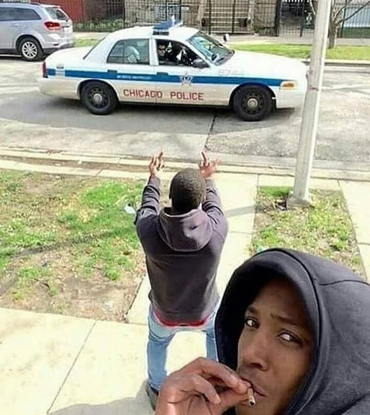 two people standing on the sidewalk in front of a police car and one person holding up a string