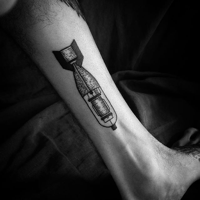 a person with a tattoo on their arm holding a toothbrush in his right hand