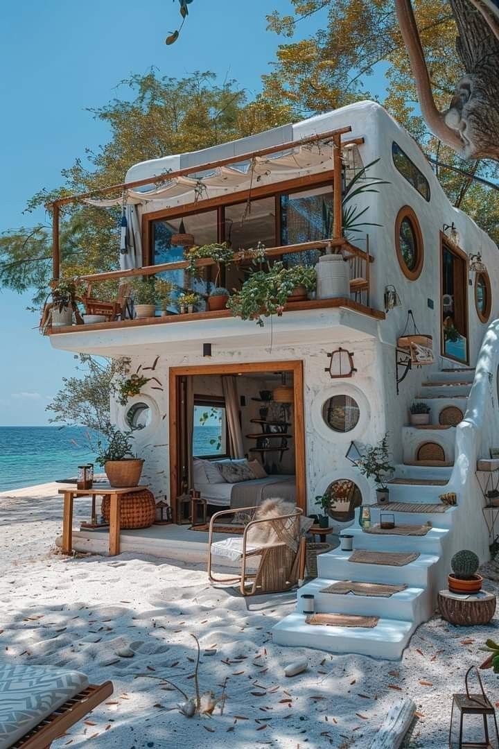 a small house on the beach with stairs leading up to it's second floor