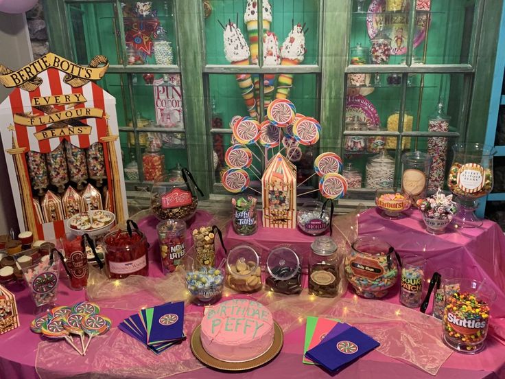 a table topped with lots of candy and candies next to a carnival booth window