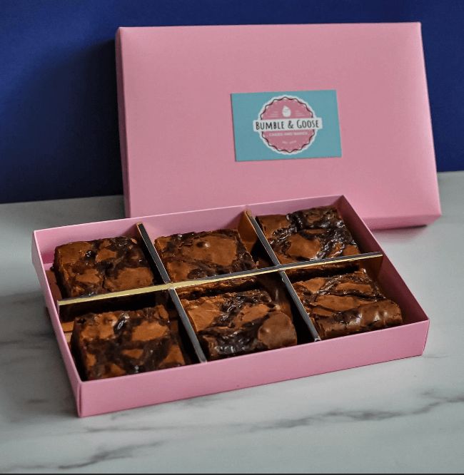 a pink box filled with brownies sitting on top of a white marble countertop