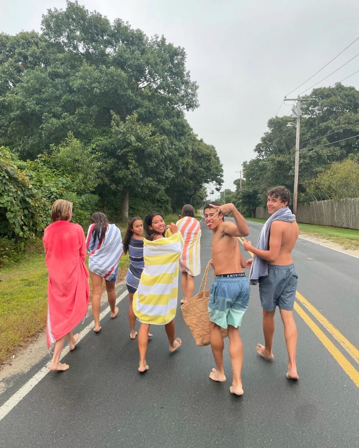 a group of people walking down the road with towels wrapped around their necks and arms