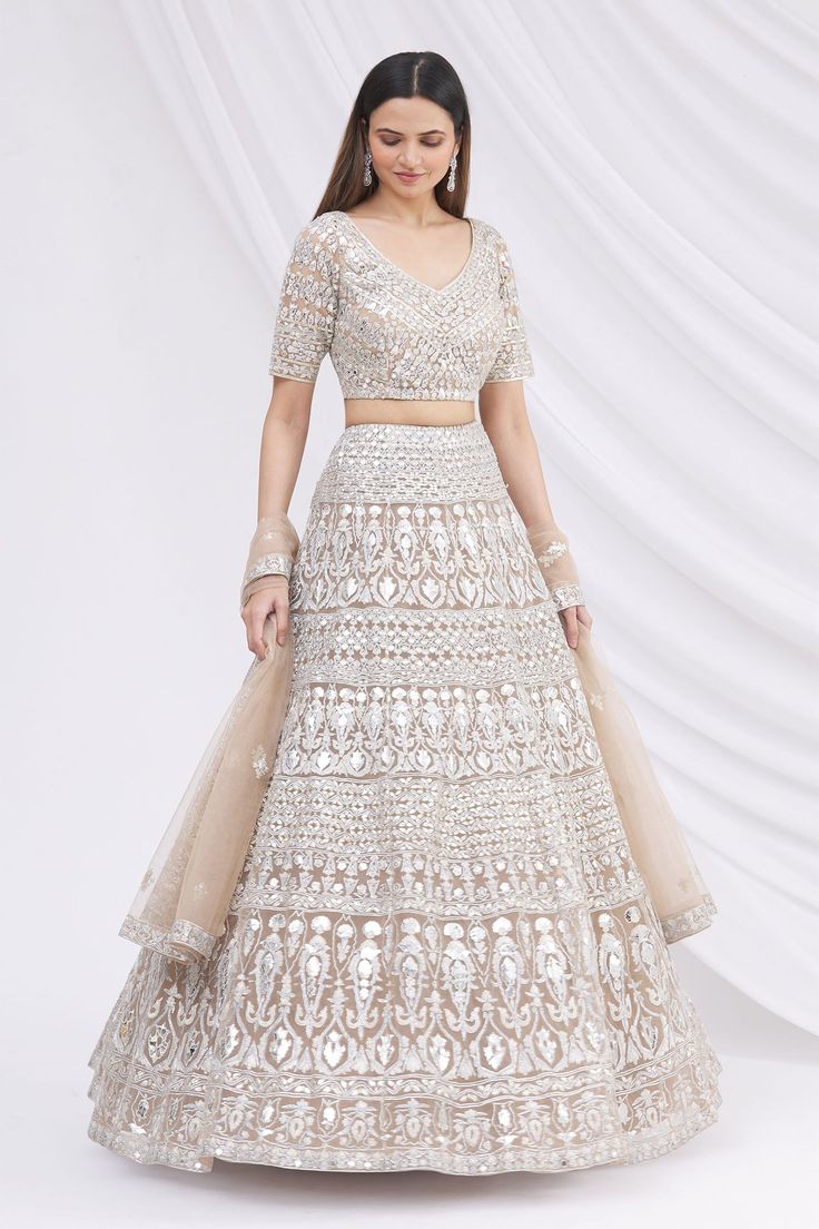 Beige lehenga with mirror embroidered motifs. Comes with blouse and sheer dupatta. Components: 3 Fabric: Net Neckline: Scoop Sleeve Length: Short Color: Beige Embroidery Mirror embroidered motifs on blouse Deep back with tassel tie-up Embroidered floral motifs on dupatta Closure: Concealed back hook placket on blouse - Aza Fashions Saree Gown Designer, Embroidered Bridal Lehenga, Saree Gown, Lehenga Skirt, Embroidered Lehenga, Bridal Lehenga, Indian Design, Set For Women, Festival Wear