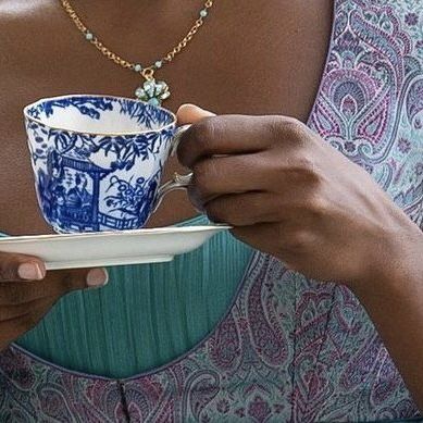 a woman holding a cup and saucer in her hands