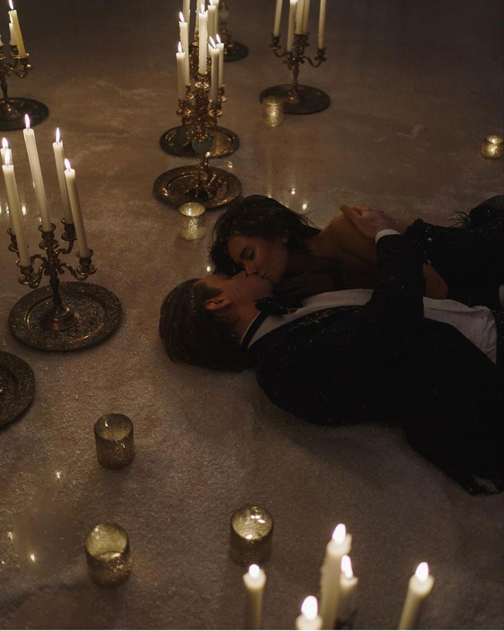 a woman laying on the ground surrounded by candles