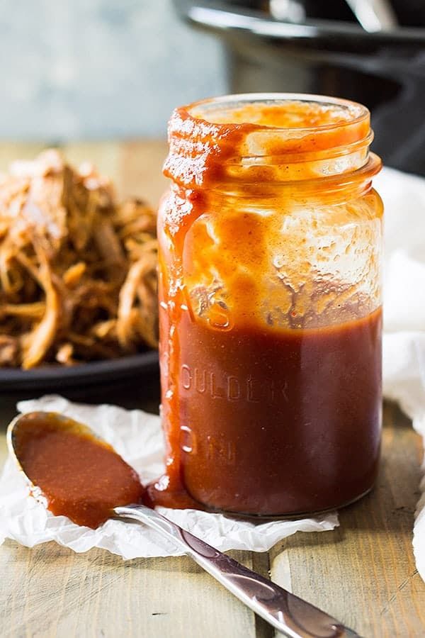 a jar of bbq sauce next to a plate of pulled pork