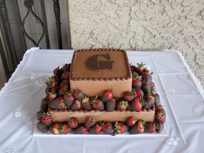 a three tiered cake with strawberries and chocolate on the top is sitting on a white tablecloth