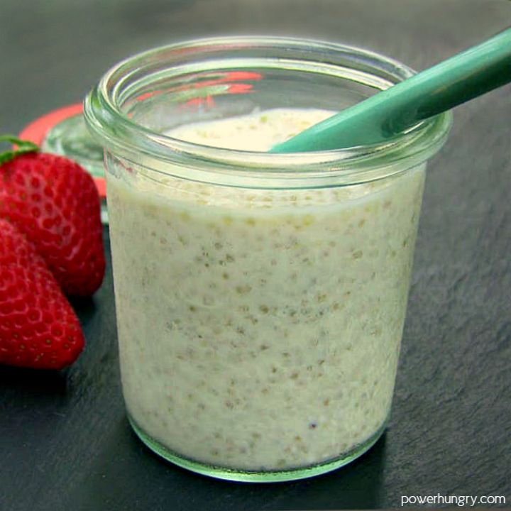 a glass jar filled with oatmeal next to two strawberries on a table