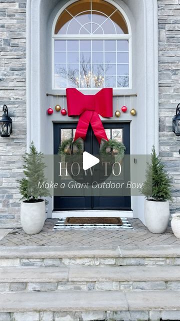 a front door with a red bow and potted plants