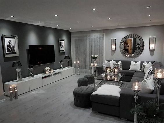 a living room filled with lots of furniture next to a flat screen tv mounted on a wall