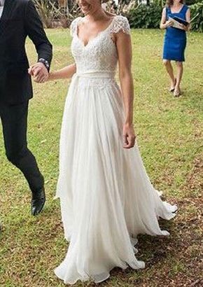 a man and woman holding hands walking in the grass with other people behind them wearing formal wear