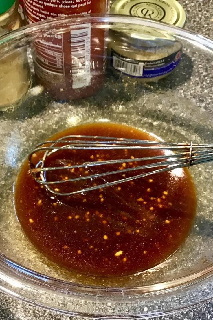 an image of sauce in a bowl with whisk on the counter top and ingredients around it