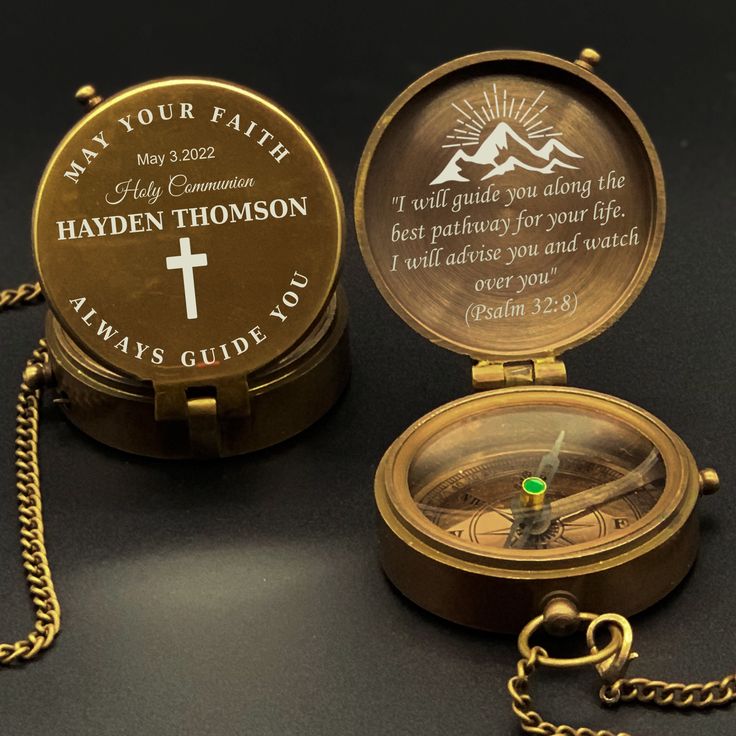 a compass with a bible verse on it and a chain around it, sitting on a black surface